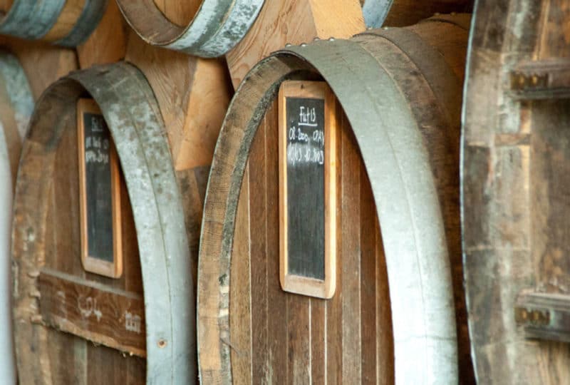 Tonneaux et fûts de calvados dans le chai de vieillissement d'une distillerie du Calvados