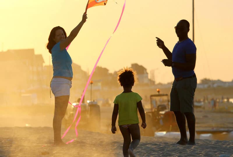 Une famille au coucher du soleil sur la plage qui jour au cerf-volant