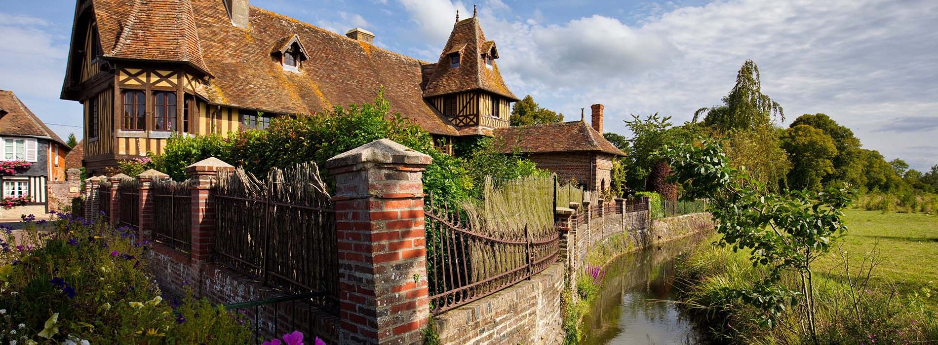 Maison en colombage dans le Calvados en Normandie, bordée d'un ruisseau