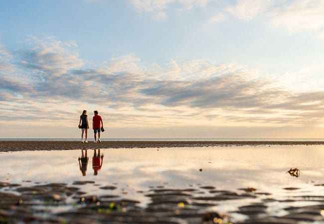 Couple se baladant sur la plage au coucher du soleil