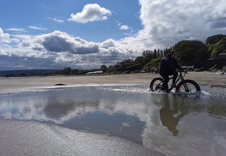 Femme faisant du fatbike sur la plage