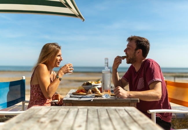 jeune couple mangeant des fruits de mer dans un restaurant au bord de la mer en Normandie