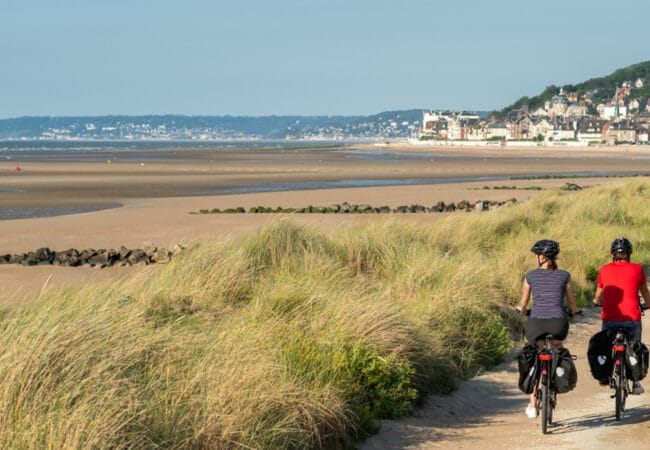 Balade en couple à vélo dans les dunes le long de la mer