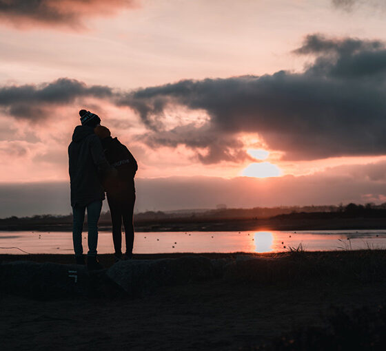 Couple regardant le coucher de soleil à la plage